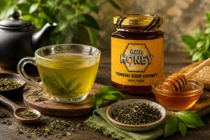 Glass mug of herbal tea next to honey jar and loose leaves for Green Tea With Honey.