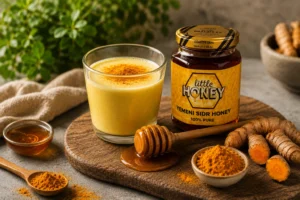 Golden turmeric milk glass beside honey jar and roots for Honey and Turmeric remedy.